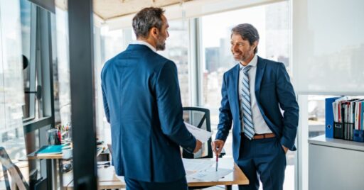 Dos empresarios discutiendo en oficina con vista a la ciudad