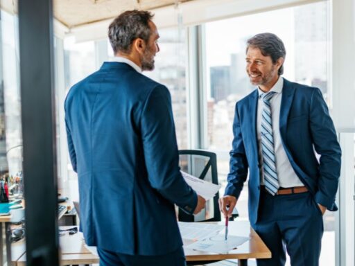 Dos empresarios discutiendo en oficina con vista a la ciudad
