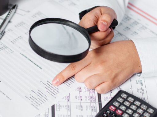 Persona revisando documentos con lupa y calculadora