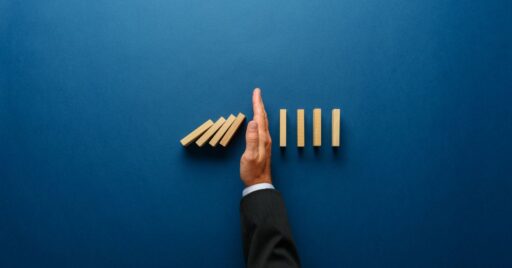 Mano deteniendo efecto dominó sobre fondo azul