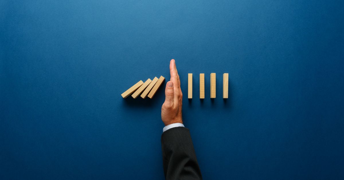 Mano deteniendo efecto dominó sobre fondo azul