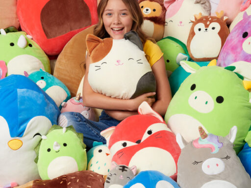 Niña sonriente rodeada de peluches coloridos