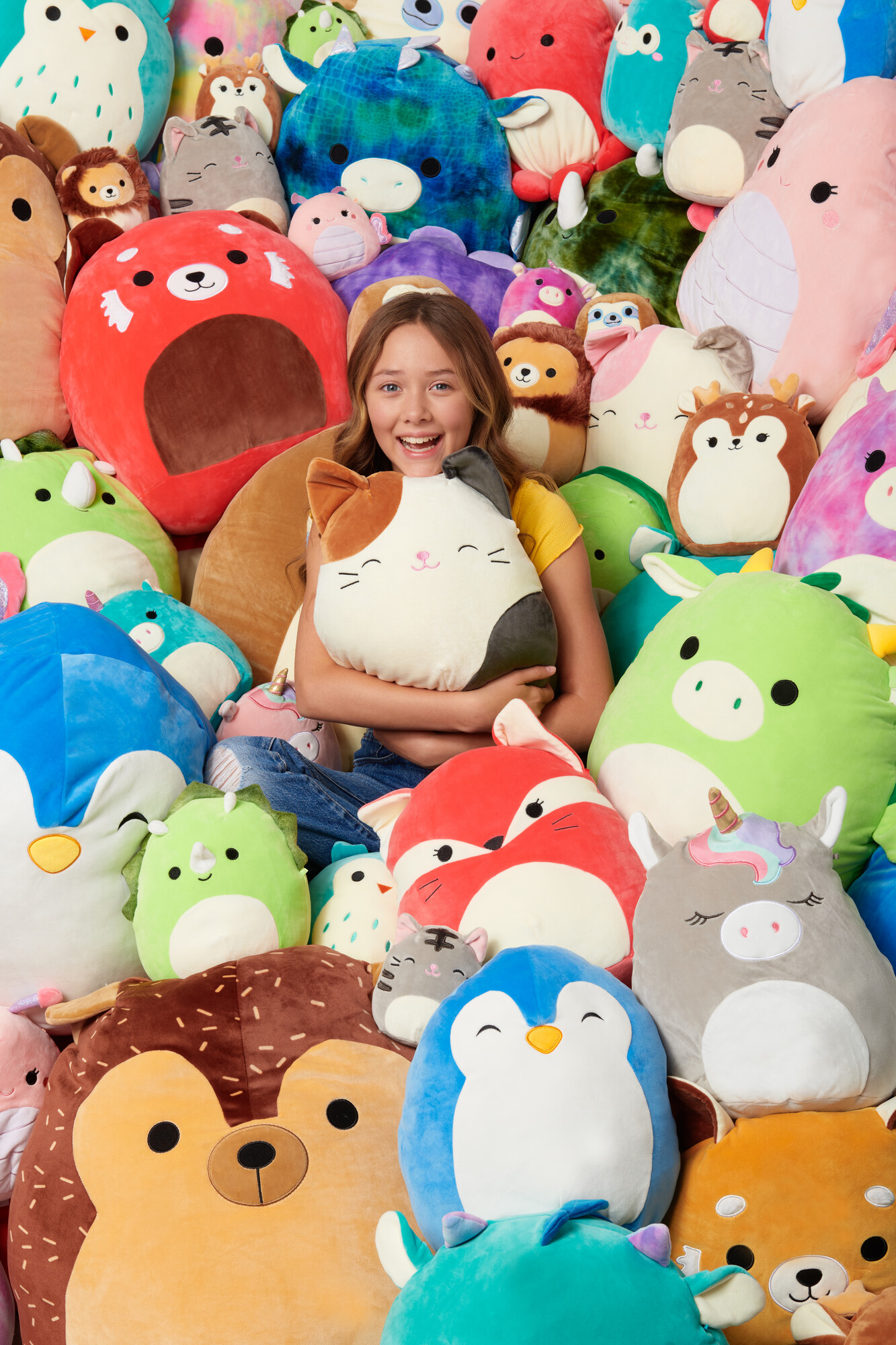 Niña sonriente rodeada de peluches coloridos