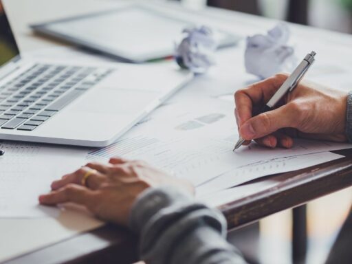 Persona trabajando en documentos con laptop y pluma