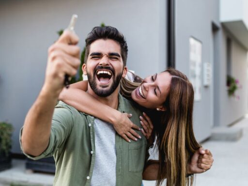 Pareja feliz tomando selfie frente a casa