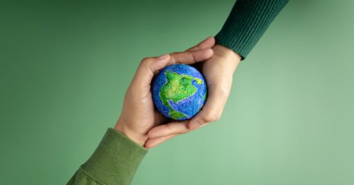 Manos sosteniendo Tierra artística sobre fondo verde