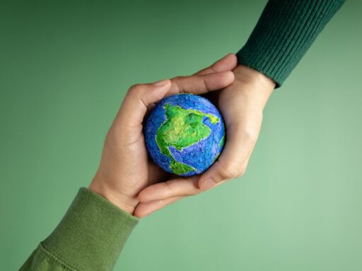 Manos sosteniendo Tierra artística sobre fondo verde