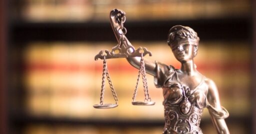 Estatua de la justicia en enfrente de libros borrosos