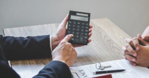Persona revisando cálculos con calculadora en reunión
