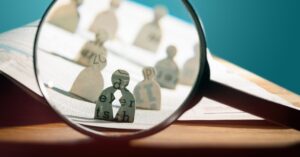 Lupa enfocando figura de persona entre otras desenfocadas