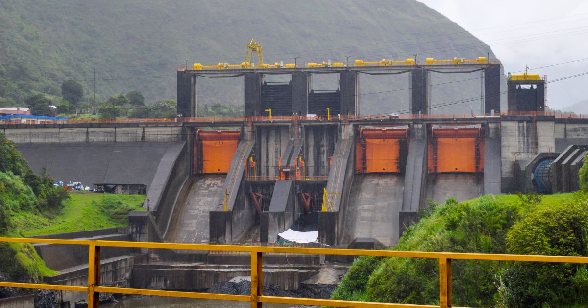 Represa hidroeléctrica con compuertas naranjas en zona verde