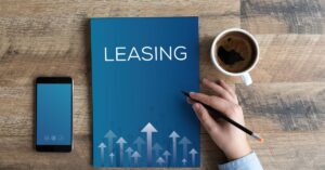Mano escribe en cuaderno azul con palabra leasing