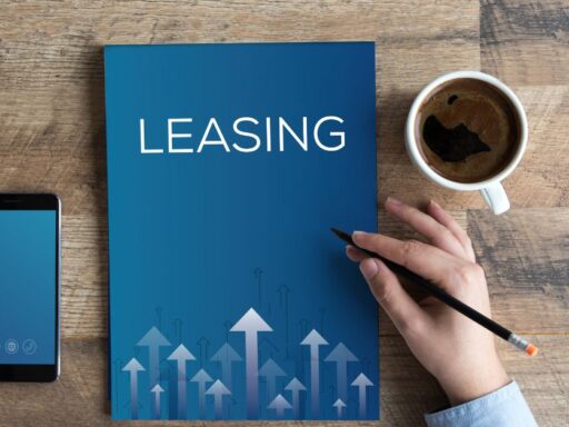 Mano escribe en cuaderno azul con palabra leasing