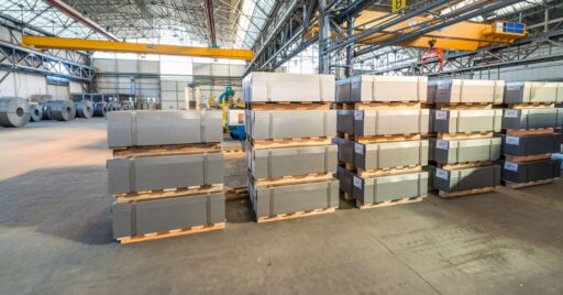 Almacén industrial con pilas de láminas y bobinas metálicas