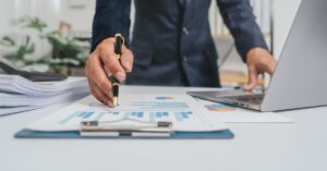 Hombre revisando gráficas junto a computadora y documentos