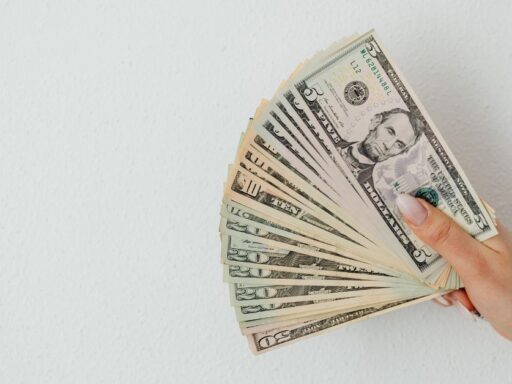 Mano sosteniendo abanico de billetes de dólares