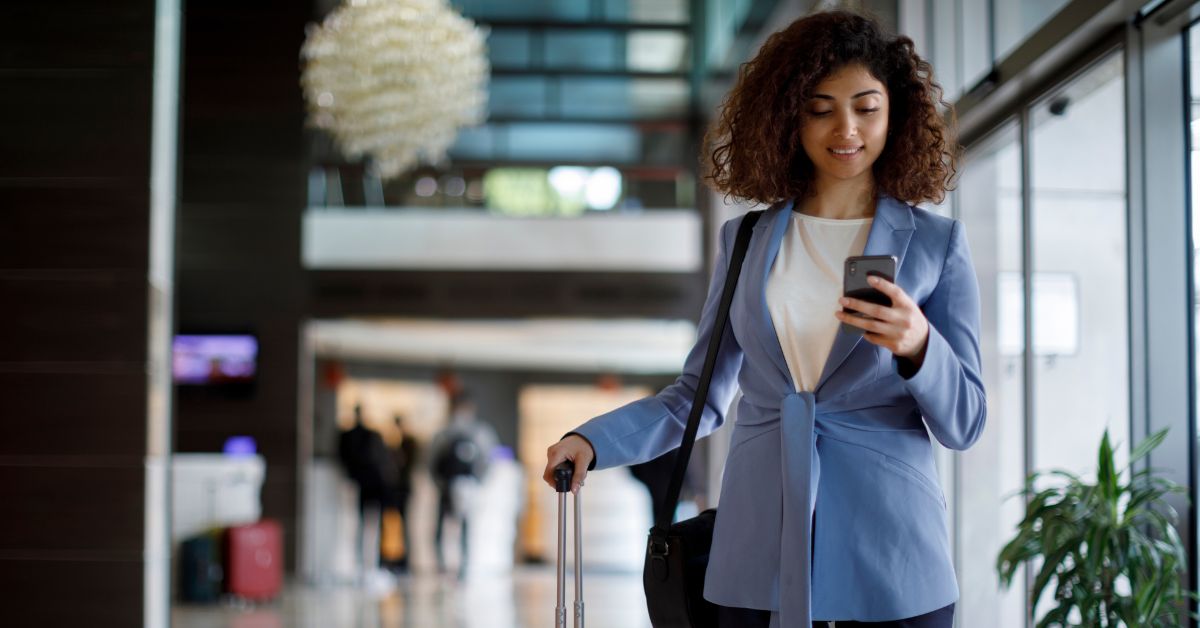 Mujer caminando en aeropuerto utilizando su celular