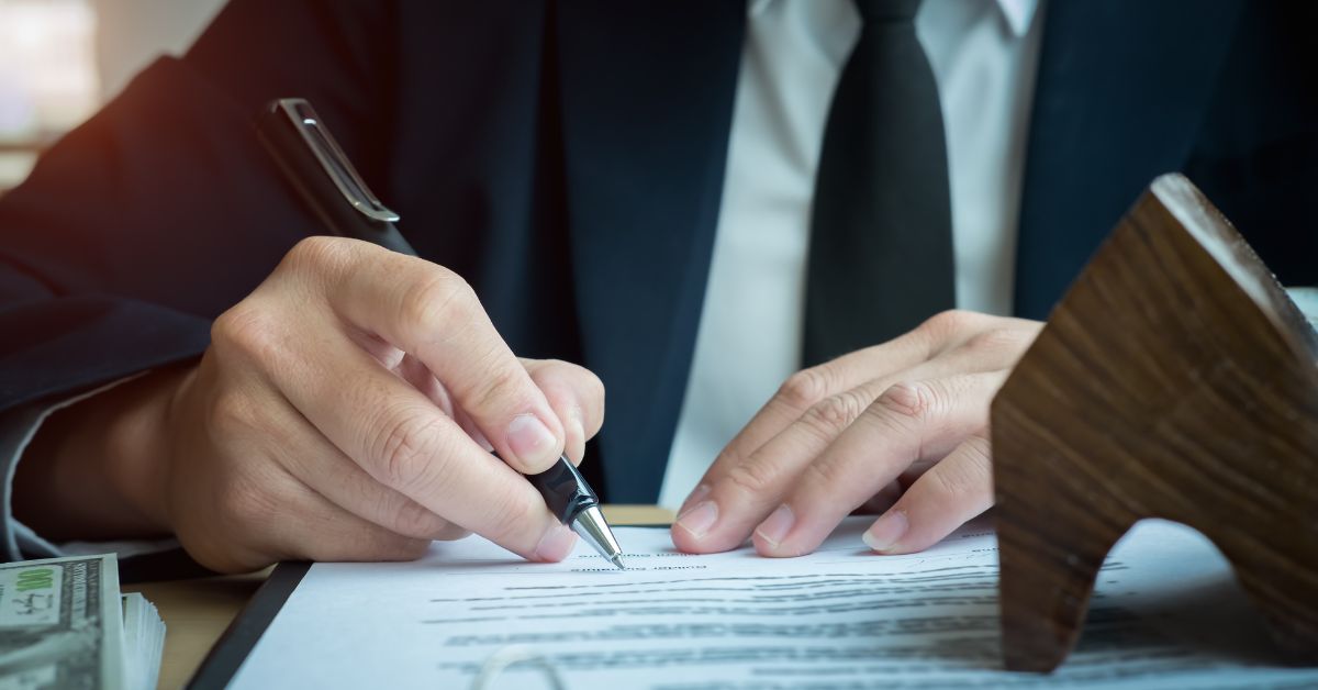 Hombre firmando documentos legales con sello y dinero