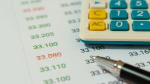Calculadora y bolígrafo sobre papel con cifras financieras