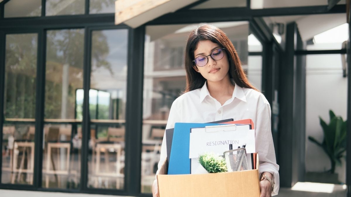 Mujer renunciando con caja de pertenencias en oficina