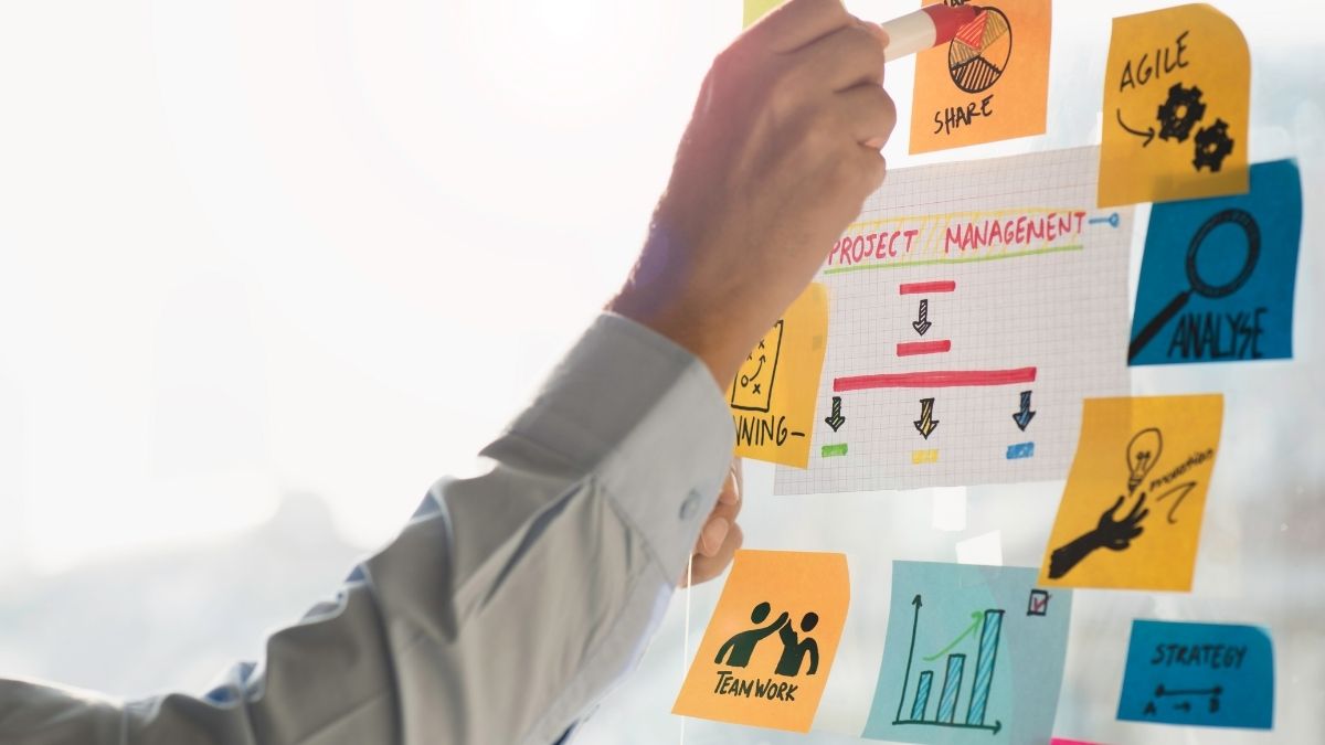 Persona planificando en pizarra con notas adhesivas coloridas