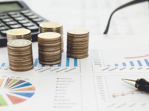 Monedas apiladas y gráficas financieras con calculadora