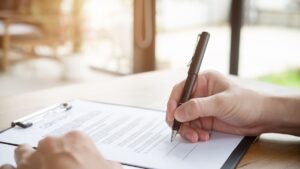 Persona firmando contrato en mesa