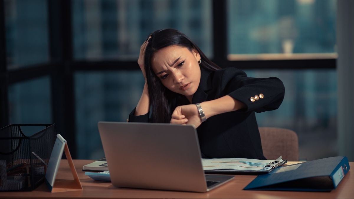 Mujer estresada revisando hora en oficina moderna