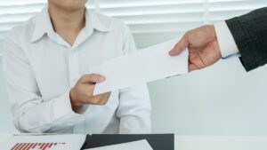 Persona entregando un sobre a otra en oficina