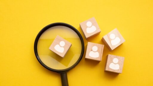 Lupa analizando íconos de personas en cubos de madera