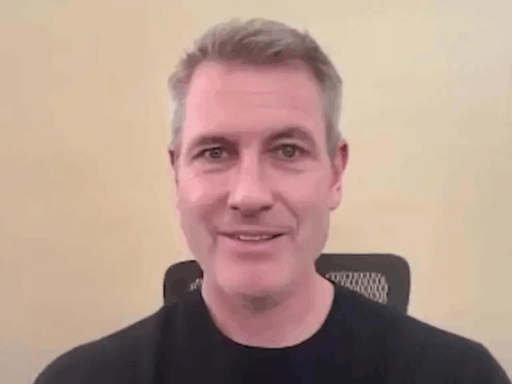 Hombre sonriente con fondo beige y camiseta negra