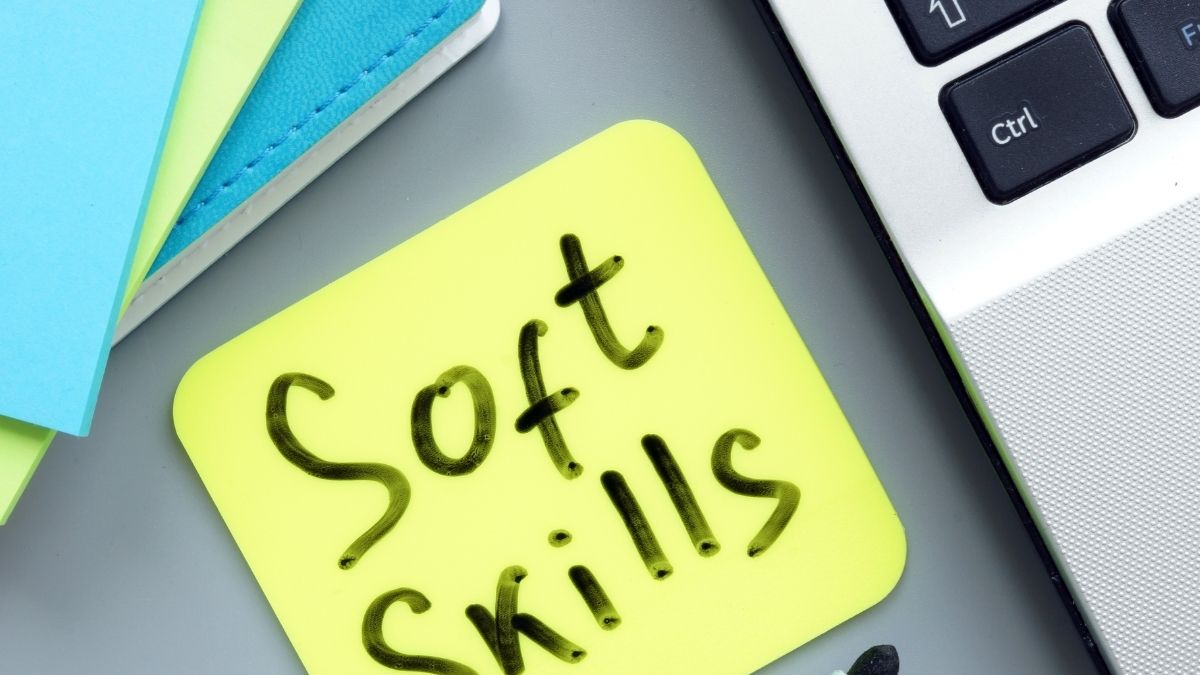 Nota amarilla con texto 'Soft Skills' cerca de laptop