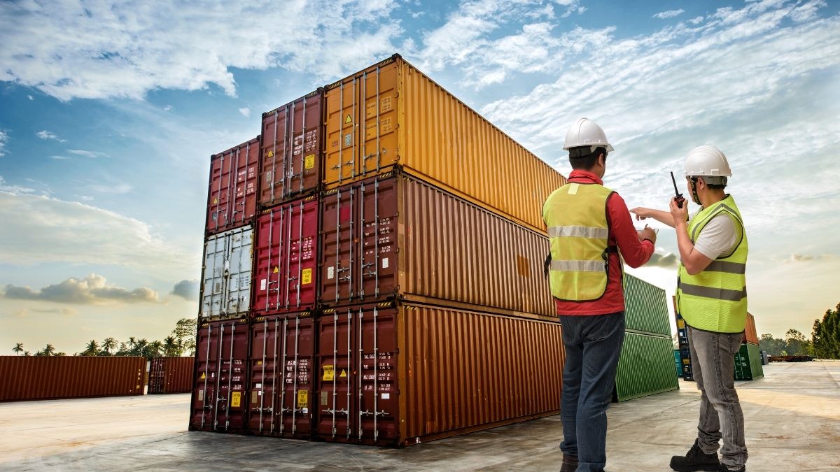 Trabajadores inspeccionando contenedores de carga al atardecer