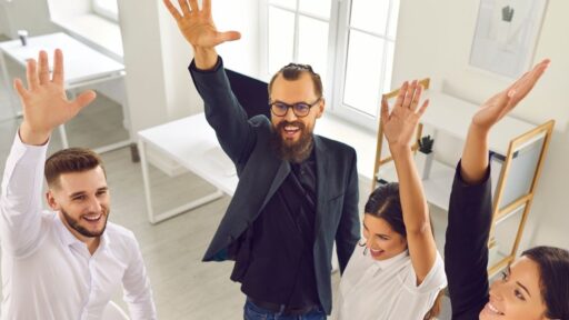 Equipo de oficina feliz levantando las manos juntos