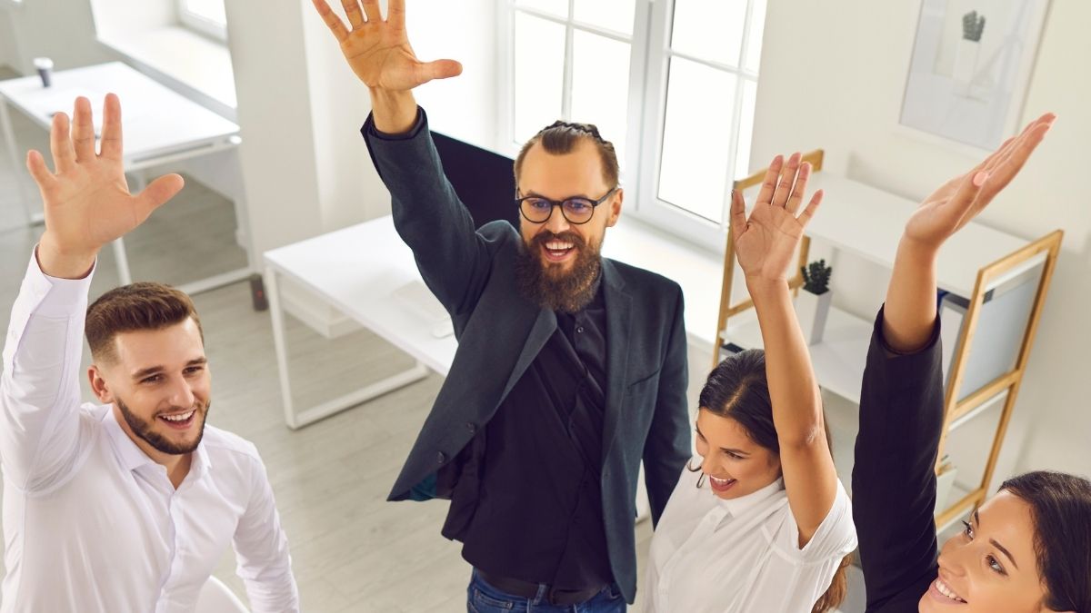 Equipo de oficina feliz levantando las manos juntos