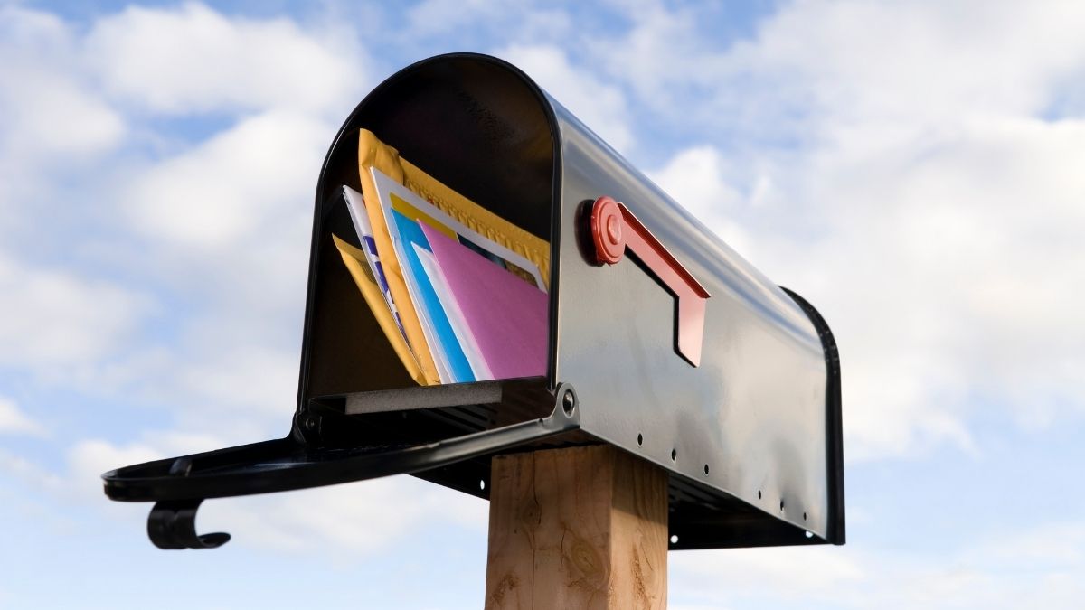 Buzón de correo lleno de sobres coloridos cielo azul