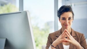 Mujer sonriente en oficina con traje sastre beige
