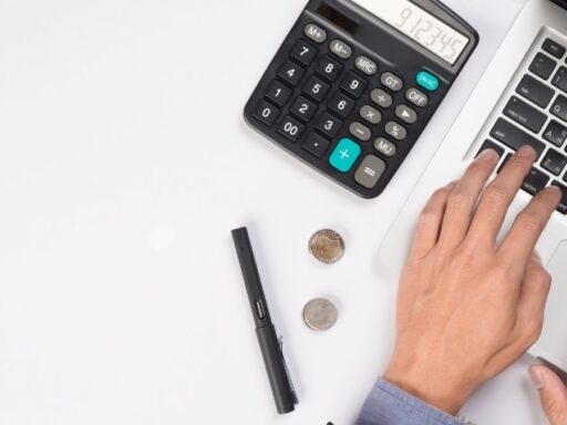 Mano trabajando con calculadora y laptop en escritorio