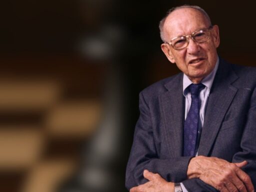 Hombre mayor en traje cruzando brazos, fondo difuso