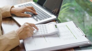 Persona trabajando con laptop y calculadora financiera