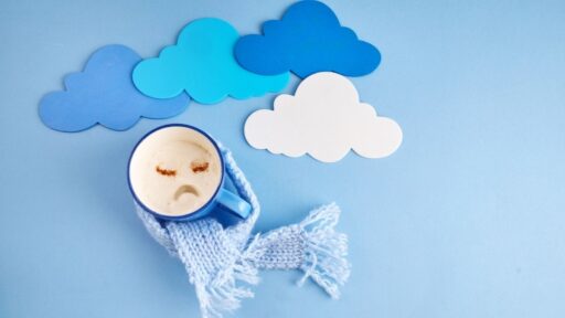 Taza con cara triste y nubes de papel